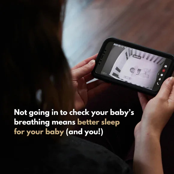 A person holds a Breathing Reassurance Newborn Baby Swaddle monitor showing a baby sleeping in a crib. Text reads: Rest easy—no need to check your baby's breathing for better sleep for both of you!.