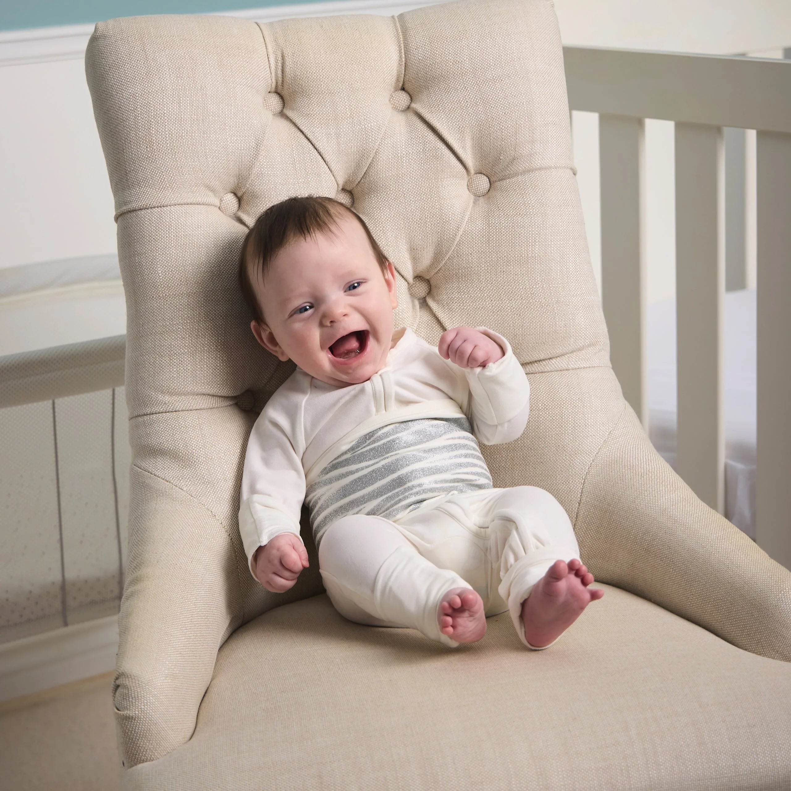 Baby in pajamas sitting in chair in nursery