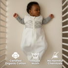 Baby lying in a white organic cotton sleep bag with certification icons displayed.