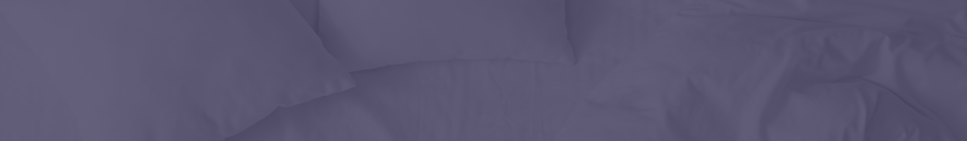 A close-up view of an unmade bed with two pillows and wrinkled sheets, all in a solid, deep blue color.