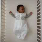 Baby sleeping with a Sleep of Mind sleep sack on in a white crib 