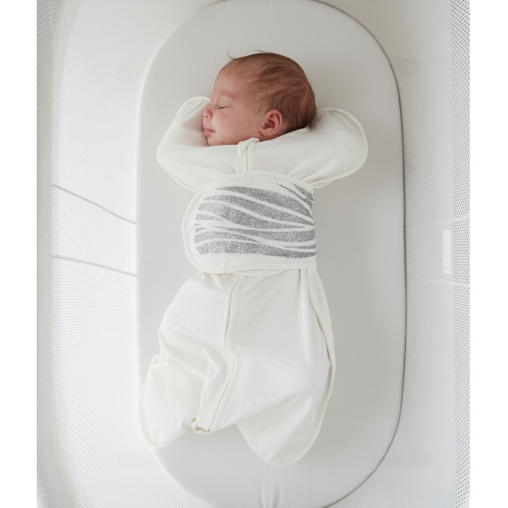 Newborn baby swaddled in a white and gray striped blanket lying on a white crib.